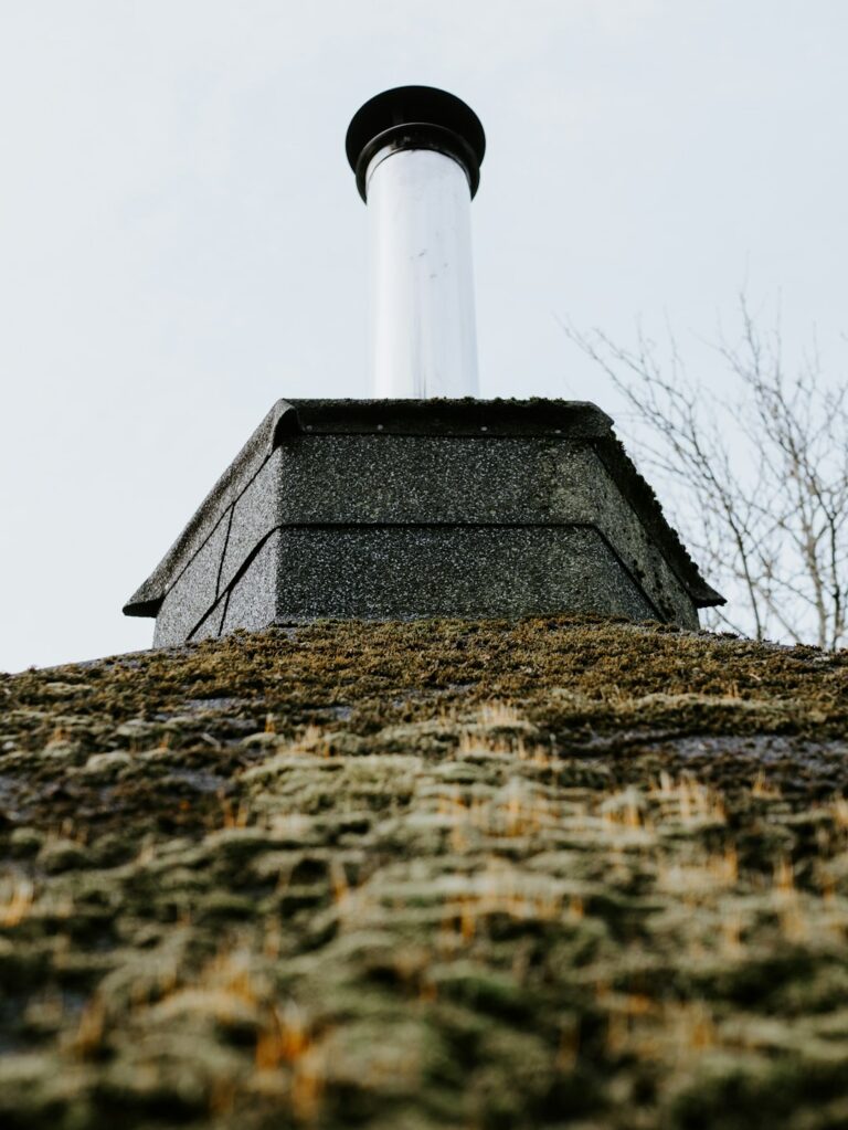 Uneven shingles and exposed flashing visible on a residential roof beside a damp attic ceiling stain.